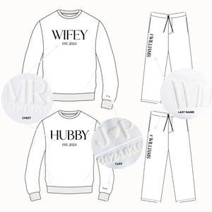 May include: A white sweatshirt with the text "WIFEY EST. 2024" on the front, a white sweatshirt with the text "HUBBY EST. 2024" on the front, and a pair of white sweatpants with the text "WILLIAMS" on the side.