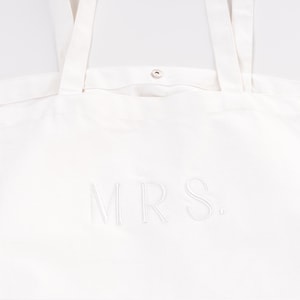 Peut inclure: Sac fourre-tout en toile blanche avec le mot "MRS." brod&eacute; en fil blanc.