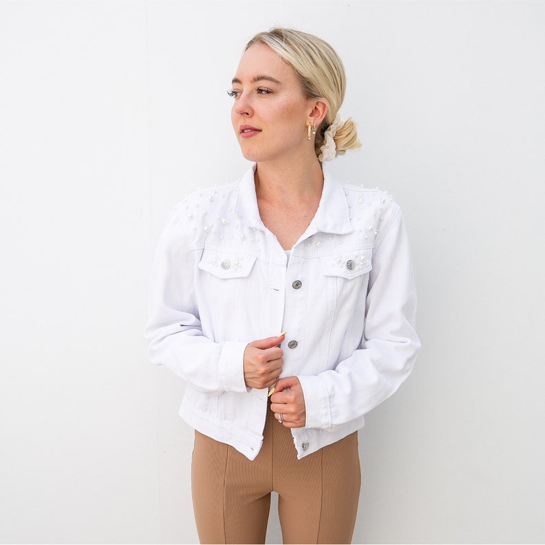 Personalized bridal denim jacket. Made from soft denim and decorated with faux pearls for a chic look. White jean jacket custom embroidered with your name. Perfect to wear for an engagement photoshoot.