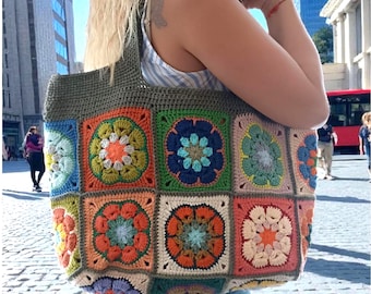 May include: A large tote bag constructed from multi-colored crochet granny squares featuring floral motifs in shades of orange, blue, green, and cream. The bag has a solid olive green crochet top border and two matching olive green shoulder straps.