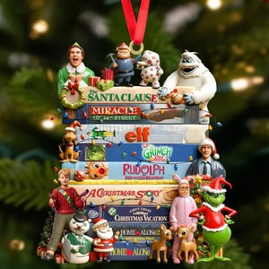 May include: A Christmas-themed ornament featuring stacked movie titles like "Elf" and "Home Alone," with character figurines from the films. The ornament includes a red ribbon for hanging and is decorated with miniature lights.