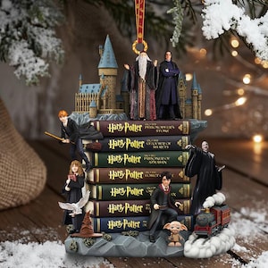 May include: A detailed Harry Potter-themed ornament featuring miniature figures of characters and iconic elements. The ornament includes a stack of books with titles, a Hogwarts castle, and a train. The figures include Dumbledore, Snape, Harry, Ron, Hermione, and Voldemort.