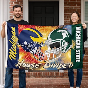 May include: A flag featuring two football helmets, one navy blue and yellow, the other green and white. The flag reads "Michigan" and "Michigan State" with the words "House Divided" below the helmets.