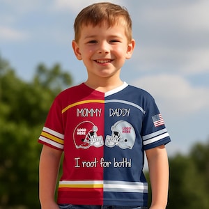 May include: A youth-sized football jersey-style t-shirt. The shirt is split vertically, with a red side and a navy blue side. The red side has a football helmet graphic and the text "Mommy". The navy side has a football helmet graphic and the text "Daddy". The shirt also has the text "I root for both!"