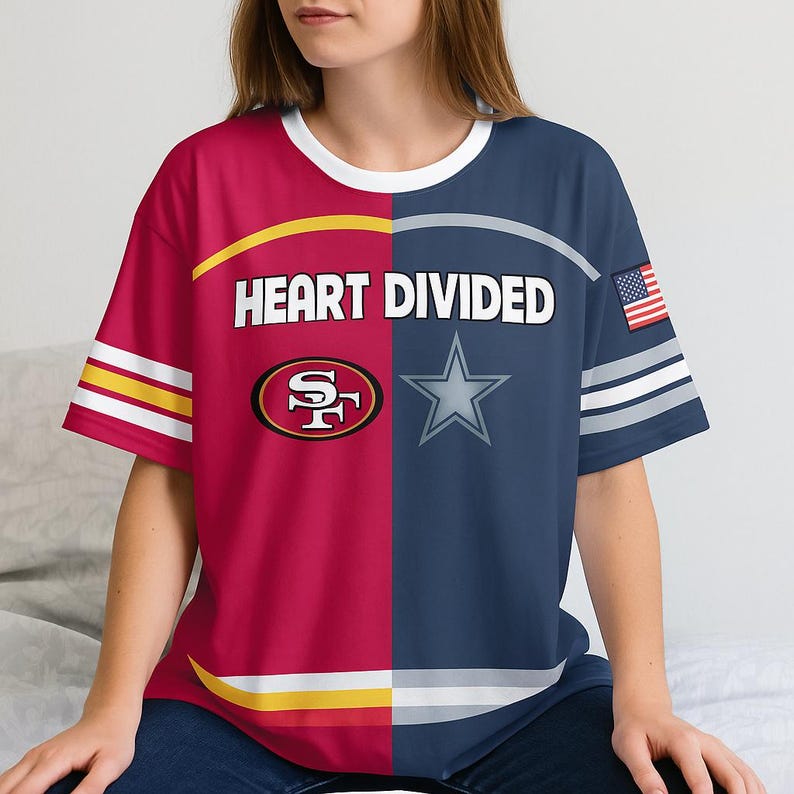 May include: A split-design t-shirt with the text "HEART DIVIDED". One side is red with a gold and white stripe, the other is navy blue with a white star and an American flag. The shirt features the logos of the San Francisco 49ers and the Dallas Cowboys.
