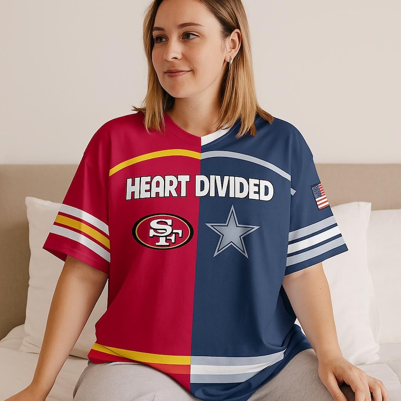 May include: A short-sleeved t-shirt with a split design. One side is red with the San Francisco 49ers logo, and the other is navy blue with the Dallas Cowboys star logo. The shirt has the text "HEART DIVIDED" across the chest.