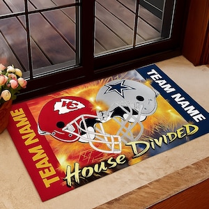 May include: A rectangular doormat featuring two football helmets, one red and one silver, set against a backdrop of yellow and orange fireworks. The words "Team Name" and "House Divided" are prominently displayed.