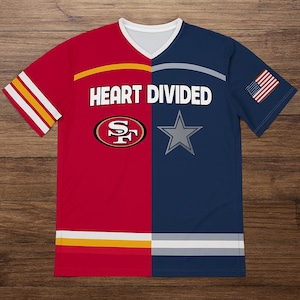 May include: A split-design v-neck t-shirt. The left side is red with yellow and white stripes, and the San Francisco 49ers logo. The right side is navy blue with a gray star and an American flag. The text "HEART DIVIDED" is across the center.