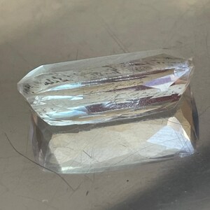 K&ouml;nnte beinhalten: Ein klarer, facettierter Edelstein mit rechteckiger Form. Der Edelstein hat mehrere Facetten, die das Licht reflektieren und einen funkelnden Effekt erzeugen. Der Edelstein ist wahrscheinlich ein Kristall oder ein geschliffenes Glasst&uuml;ck.