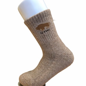 Puede incluir: Un par de calcetines de lana marrón con un logotipo de búfalo marrón y el texto "YPK" en el lateral.