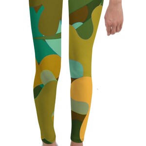 Może przedstawiać: Zielone, żółte i brązowe legginsy z abstrakcyjnym nadrukiem kwiatowym dla dzieci. Legginsy są wykonane z miękkiej, elastycznej tkaniny i idealnie nadają się do codziennego noszenia.