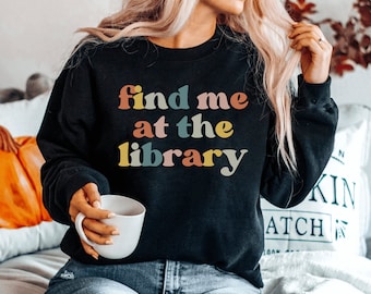 May include: A black sweatshirt with the text "find me at the library" in colorful retro-style lettering.