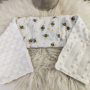 May include: White baby burp cloth with a white and yellow bee pattern. The burp cloth has a textured surface with small white bumps.