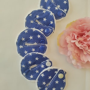 May include: Five blue and white fabric burp cloths with white stars and a white fuzzy trim. Each cloth has a blue or white snap button.
