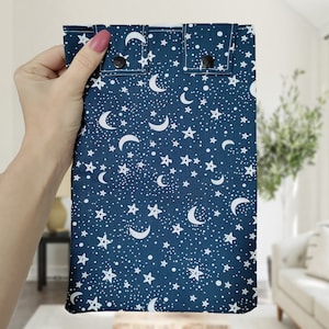 May include: A dark blue fabric pouch with a white moon and star pattern. The pouch has two snap closures.