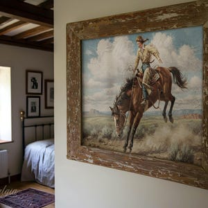 Puede incluir: Una pintura enmarcada de una persona montando un caballo marr&oacute;n en un campo. El caballo se est&aacute; levantando sobre sus patas traseras, y la persona est&aacute; sujetando las riendas. La pintura est&aacute; ambientada contra un cielo azul con nubes blancas.