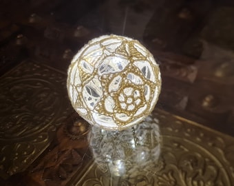 May include: A white crocheted sphere with a gold thread design, illuminated from within by a string of white lights.