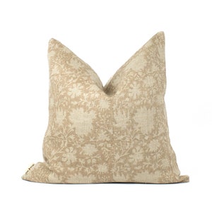 May include: A beige linen pillow with a floral pattern. The pillow is square and has a subtle sheen.