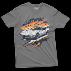 May include: Gray t-shirt with a white sports car graphic. The car is surrounded by orange and black paint splatters.