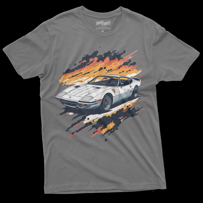 May include: Gray t-shirt with a white sports car graphic. The car is surrounded by orange and black paint splatters.