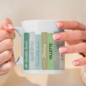 Könnte beinhalten: Weiße Keramiktasse mit einem Design aus gestapelten Büchern. Die Buchtitel lauten "Jane Eyre", "Villette", "Shirley", "Edward Rochester" und "Charlotte Bronte".
