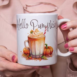Peut inclure: Une tasse en céramique blanche avec une illustration brune et blanche d'un latte à la citrouille épicée avec de la crème fouettée et une paille rouge et blanche rayée. Le texte "Hello Pumpkin" est imprimé en brun sur la tasse.