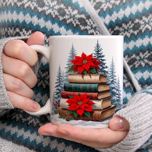 Könnte beinhalten: Weiße Keramiktasse mit einem Design aus Büchern, roten Weihnachtssternen und Tannenbäumen. Die Tasse wird von einer Person gehalten, die einen grauen Pullover trägt. Die Tasse hat einen Henkel.