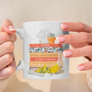 Könnte beinhalten: Weiße Keramiktasse mit einem Design aus einem Stapel Bücher mit französischen Titeln, einer kleinen Topfpflanze und einer Skulptur. Die Titel auf den Büchern sind "POESIE", "LE LAC, A.DE LAMARTINE", "Le Spleen, C.Baudelaire" und "Mienchins, allers voir la rae, P.de to".