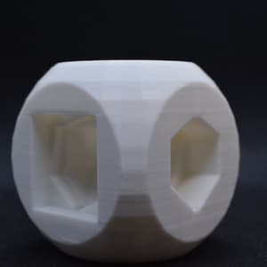 May include: A white, geometrically shaped object with three different shaped cutouts. The object is made of a smooth, white material and has a slightly textured surface.
