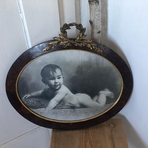 Może przedstawiać: Biały ceramiczny kubek z czarnym uchwytem i napisem "But First, Coffee" czarną, odręczną czcionką. Kubek stoi na białej powierzchni.