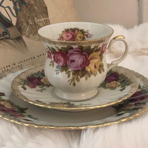 Könnte beinhalten: Ein weißes Tee-Set mit floralem Design, das rosa, gelbe und rote Rosen zeigt. Das Set hat einen goldenen Rand und ist mit einem zarten Blumenmuster verziert.