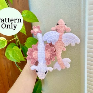 May include: Two crocheted plush sea dragon toys, one pink and one lavender, with a flower detail on the head.