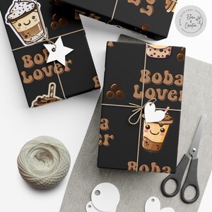 May include: Black and brown gift wrap with a boba tea design. The wrap features a cartoon boba tea cup with a smiling face, brown boba pearls, and the text "Boba Lover" in a retro font.