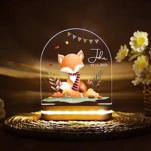 Könnte beinhalten: Ein Nachtlicht aus Holz mit einer klaren Acrylglocke, die einen Cartoon-Fuchs mit Schal zeigt, umgeben von Herbstblättern. Die Glocke trägt den Namen "John" und das Datum "23.11.2023" aufgedruckt.