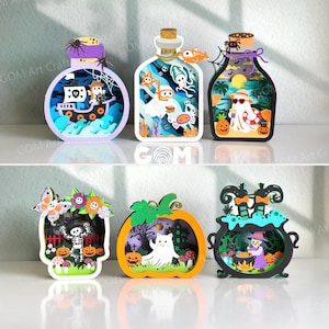 May include: A set of six layered wooden decorations featuring Halloween themes. The top row shows three bottle-shaped designs with a pirate ship, an underwater ghost scene, and a beach ghost. The bottom row includes a skull, a pumpkin, and a cauldron.
