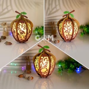 Peut inclure: Une lampe en bois en forme de gland avec un motif découpé d'oiseaux et de feuilles. La lampe est allumée et diffuse une lueur chaude.
