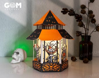 May include: A Halloween-themed paper lantern with an orange and black color scheme. The lantern features cut-out designs of skeletons and pumpkins. The top of the lantern is orange with black accents. The text "GOM Art Craft" is visible.