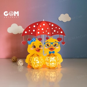 May include: Two yellow duck paper lanterns with red hearts and a red and white polka dot umbrella. The lanterns have a cut-out design of hearts and the word "love".