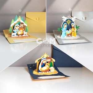 Pu&ograve; includere: Tre biglietti di Natale pop-up con un presepe. Ogni biglietto ha una combinazione di colori diversa, con Maria, Giuseppe e Ges&ugrave; bambino come figure principali. I biglietti sono aperti, rivelando il design 3D, con buste sullo sfondo.