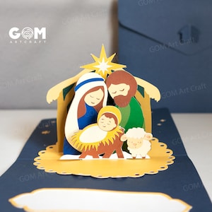 Pu&ograve; includere: Un biglietto di Natale pop-up con un presepe. Il biglietto raffigura Maria, Giuseppe e il bambino Ges&ugrave; in una mangiatoia, con una stella sopra. Il biglietto &egrave; realizzato in carta a strati nei toni del blu, giallo, marrone e bianco. Il biglietto ha il testo "GOM Art Craft".