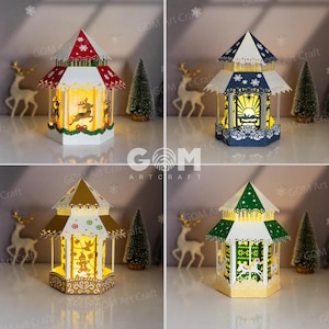May include: Four different papercraft Christmas light-up houses. Each house is a different color and has a different design. The houses are all lit up and have a warm glow.