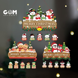 Op de afbeelding: Drie hangende kerstborden met feestelijke figuren zoals sneeuwpoppen, peperkoekmannetjes en pinguïns. Elk bord toont de tekst MERRY CHRISTMAS en bevat vijf kleine bungelende ornamenten met de namen Ben, Tom, Rien, Jona en Alit.