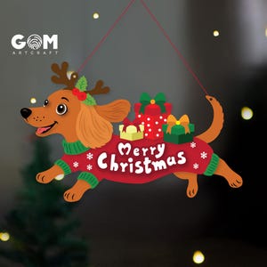 May include: A hanging ornament featuring a brown dachshund wearing a red sweater with the text Merry Christmas and white snowflake patterns. The dog has reindeer antlers with holly and carries three colorful gift boxes on its back.