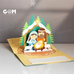 Pu&ograve; includere: Un biglietto di Natale pop-up con un presepe. Il biglietto raffigura Maria, Giuseppe e Ges&ugrave; bambino in una mangiatoia, con due agnelli. La scena &egrave; ambientata in una stalla con alberi verdi e una stella. Il biglietto &egrave; aperto e ha spazio per un messaggio.