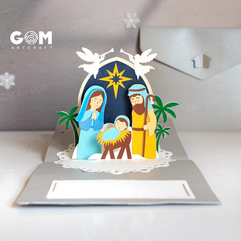 Pu&ograve; includere: Un biglietto di Natale pop-up con un presepe. Il biglietto raffigura Maria, Giuseppe e Ges&ugrave; bambino, con angeli e una stella sopra. Il biglietto &egrave; di carta e ha una combinazione di colori grigio e bianco.