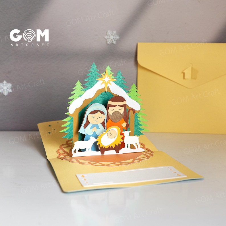 Pu&ograve; includere: Un biglietto di Natale pop-up giallo raffigurante la scena della nativit&agrave;. Il biglietto presenta un design dettagliato in carta ritagliata di Maria, Giuseppe, Ges&ugrave; bambino, alberi, una stella e pecore. Il biglietto ha il testo "GOM Art Craft".