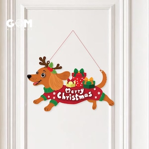 May include: A hanging wall sign featuring a brown dachshund wearing a green sweater and reindeer antlers. The dog carries three gift boxes on its back and the text Merry Christmas is printed in white on the red sweater with snowflake accents.