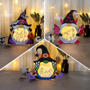 May include: Three Halloween-themed light-up gnomes. The first gnome is wearing a purple and black witch hat and holding a pumpkin. The second gnome is wearing a red and black hat with devil horns and holding a pitchfork. The third gnome is wearing a black witch hat with a spider web and holding a broom.