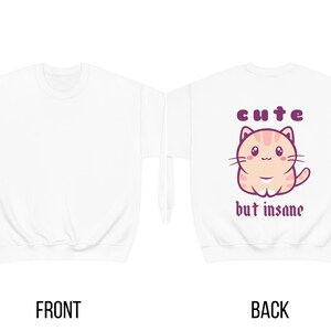 Może przedstawiać: Biała bluza z uroczym kresk&oacute;wkowym kotem i napisem "cute but insane" na plecach.