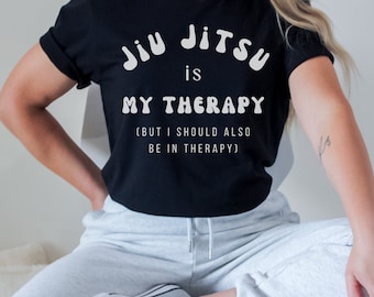 May include: Black t-shirt with white text that reads "Jiu Jitsu is my therapy (but I should also be in therapy)".